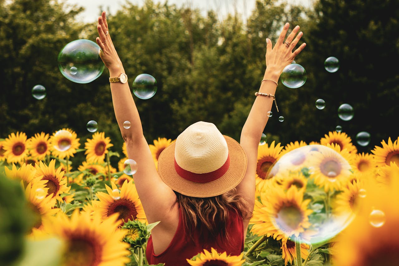 creative-01 A joyful woman in a sunflower field with bubbles, expressing happiness on a summer day.