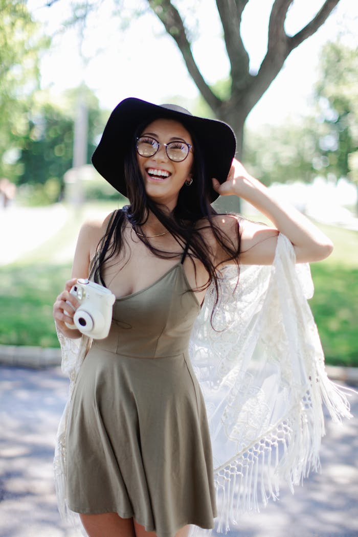 creative-02 Cheerful woman in a boho dress with a camera enjoying a sunny day outdoors.